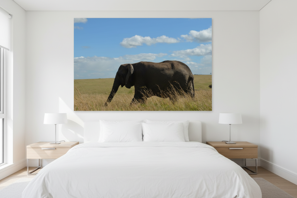 Across the Mara — Lone Elephant fine art print displayed in a bright modern luxury bedroom, white wall, linen bedding, natural daylight, no frame — Wild East Visuals