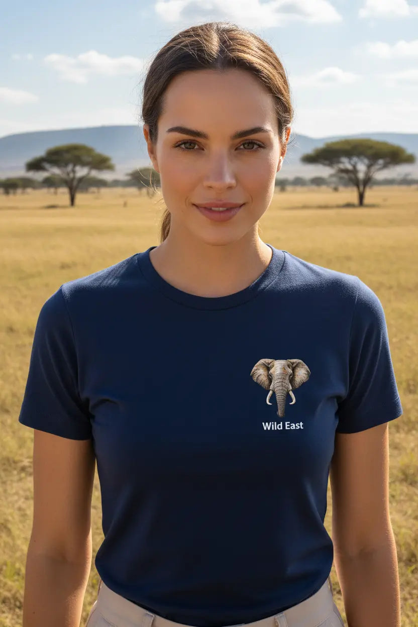 Woman wearing Wild East Navy Tee with elephant badge on left chest, standing in the African savannah — Wild East Visuals