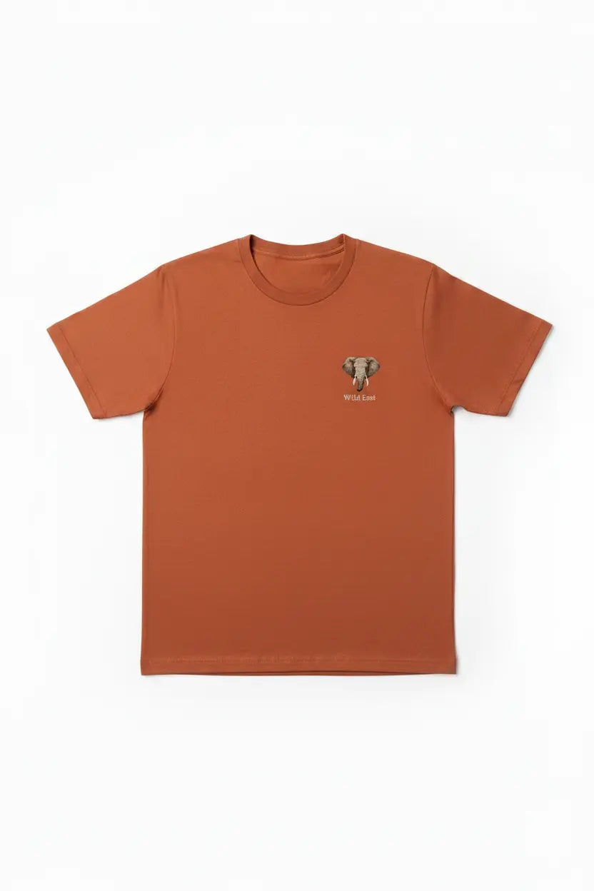 Wild East Terracotta Tee flat lay — precision elephant badge on left chest, 100% cotton, handcrafted in Nairobi — Wild East Visuals